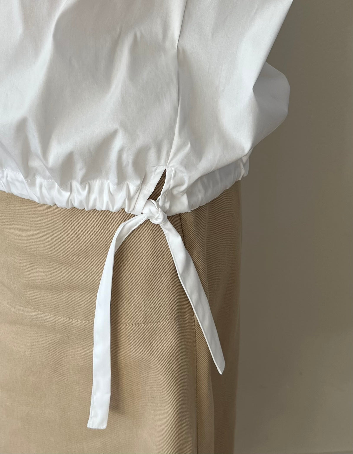 Pull in bottom hem of white poplin shirt blouse