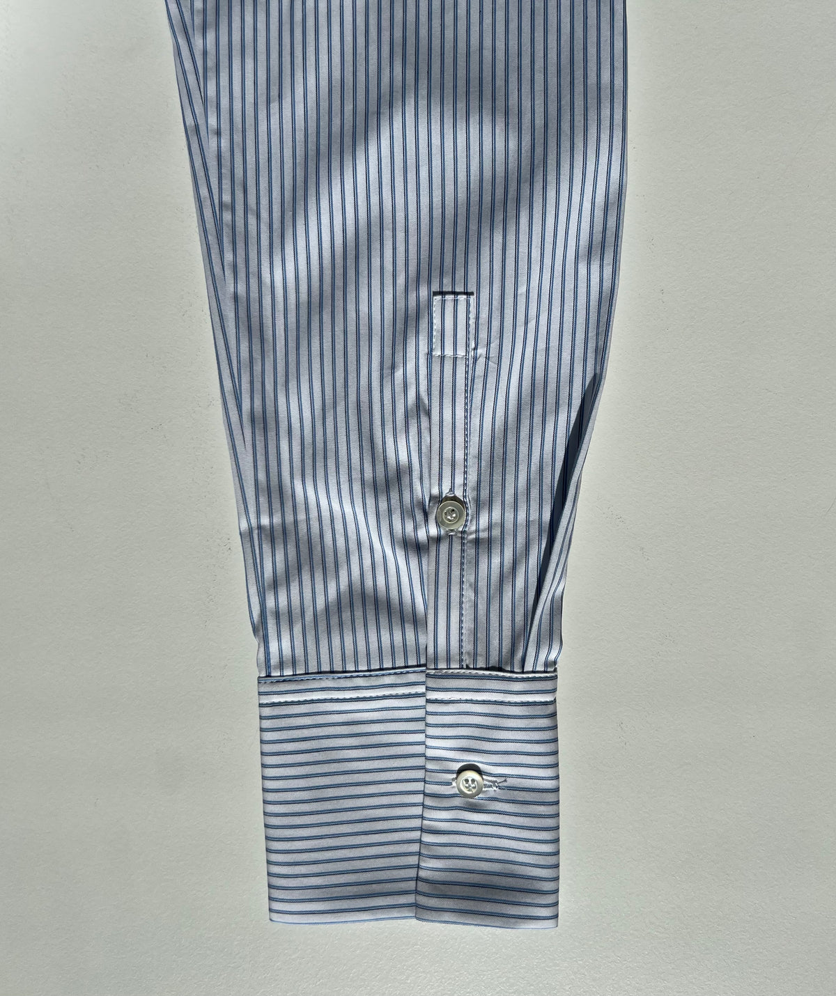 Sleeve of a striped poplin shirt in blue and white 