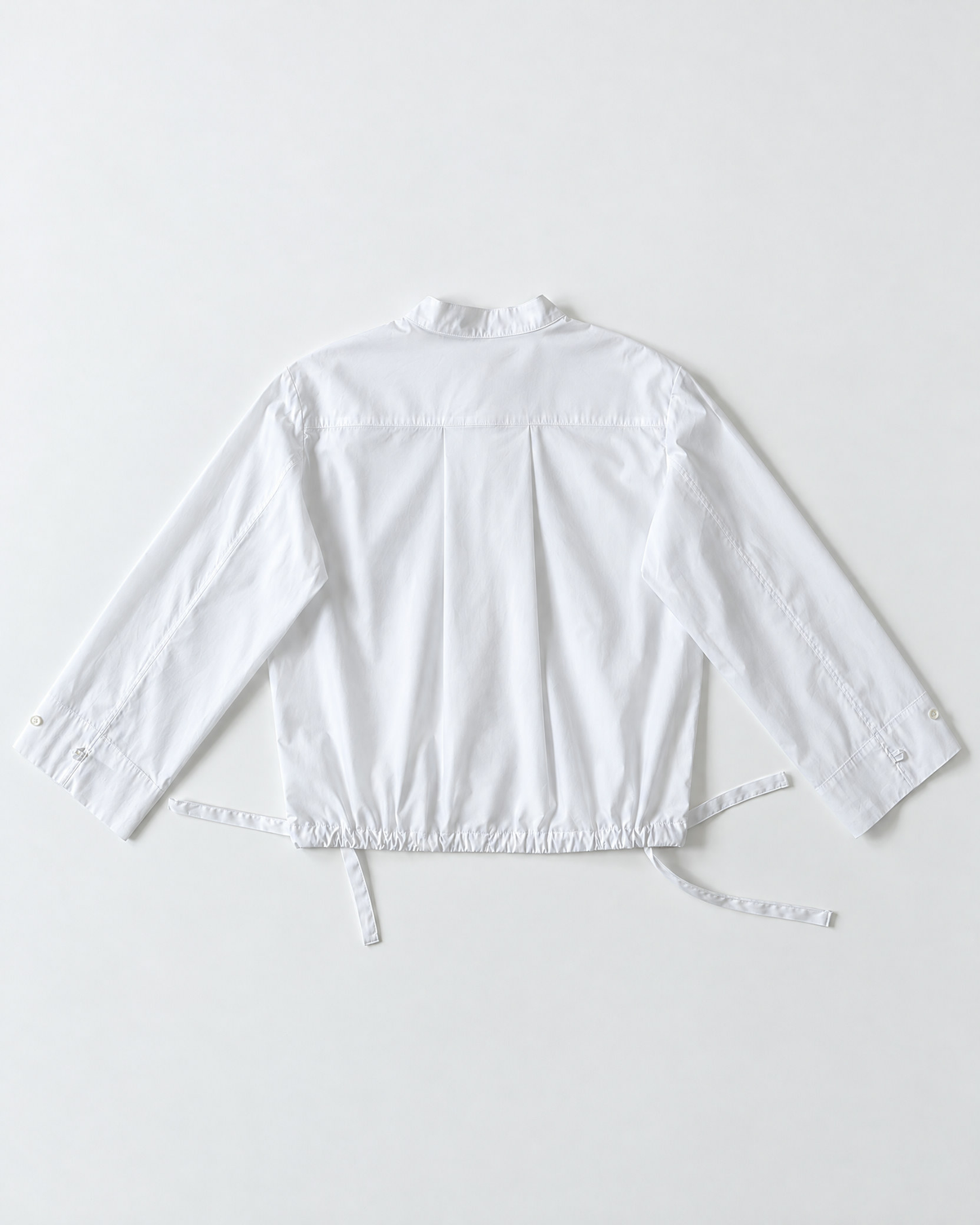 Flat lay of shirt blouse in white cotton poplin with wide sleeves.