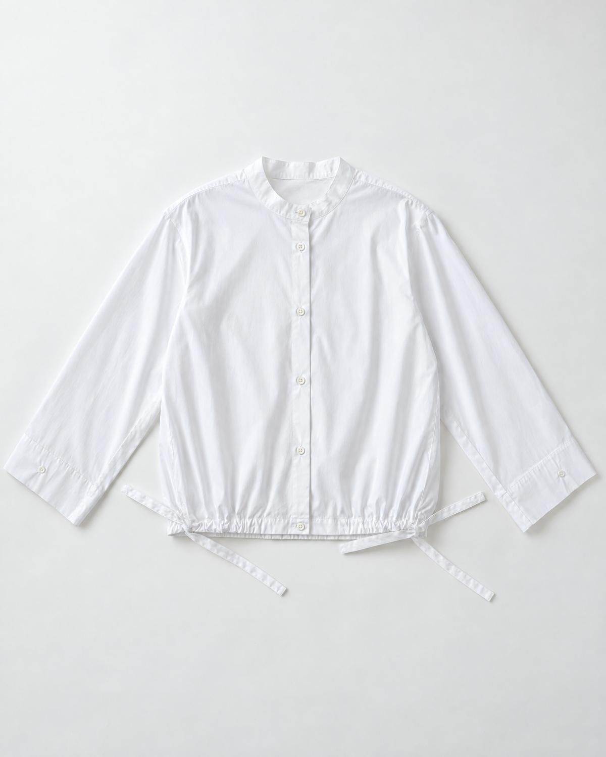 Flat lay of shirt blouse in white cotton poplin with wide sleeves and stand up collar